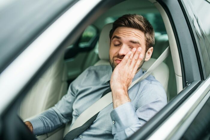 Man feeling sleepy and tired while sitting in a car, illustrating unexpected and bizarre ways people passed away.