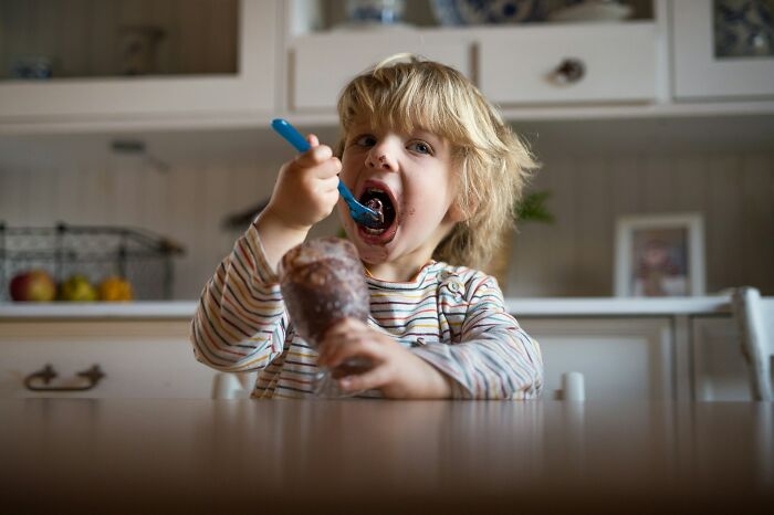 Young child eating chocolate dessert with a spoon, illustrating a story about weaponized incompetence and innocent behavior.