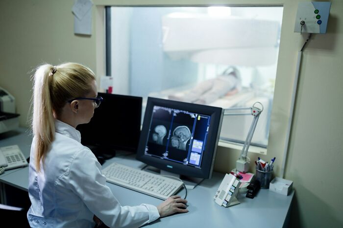 A doctor reviews MRI scans, showing how people competed over the worst MIL stories, mirroring diagnostic challenges.
