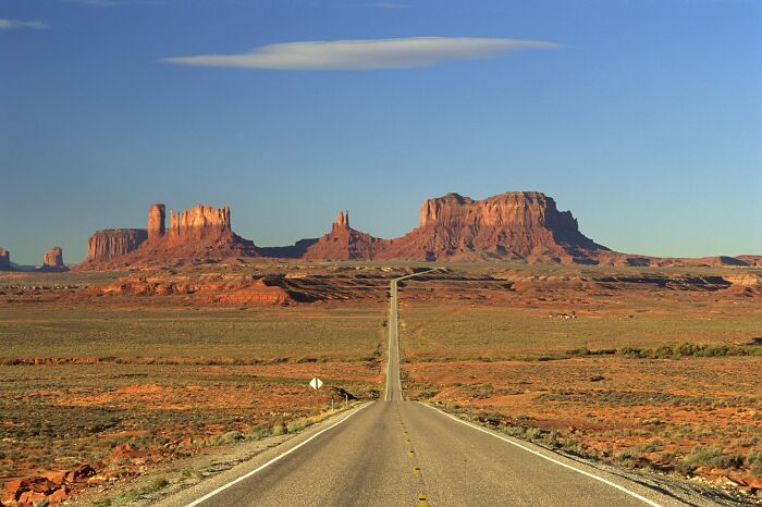 Desert highway leading toward red rock formations in one of the worst places in the US that people have visited.