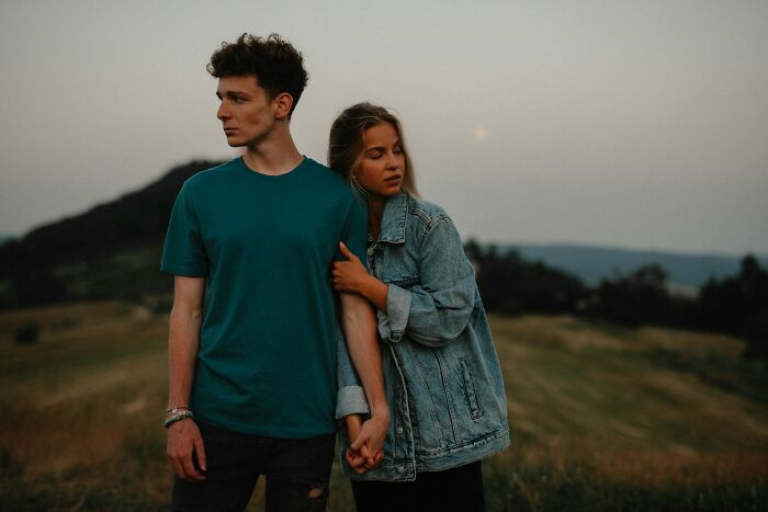 Young couple in a field showing emotions of betrayal and shock after being a good person in a tense moment outdoors