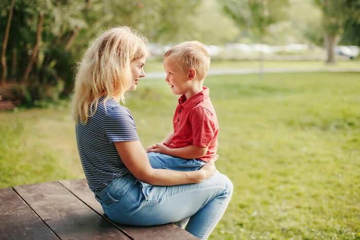 Mother and child sitting outdoors, sharing parenting tips and tricks in a peaceful green park setting.