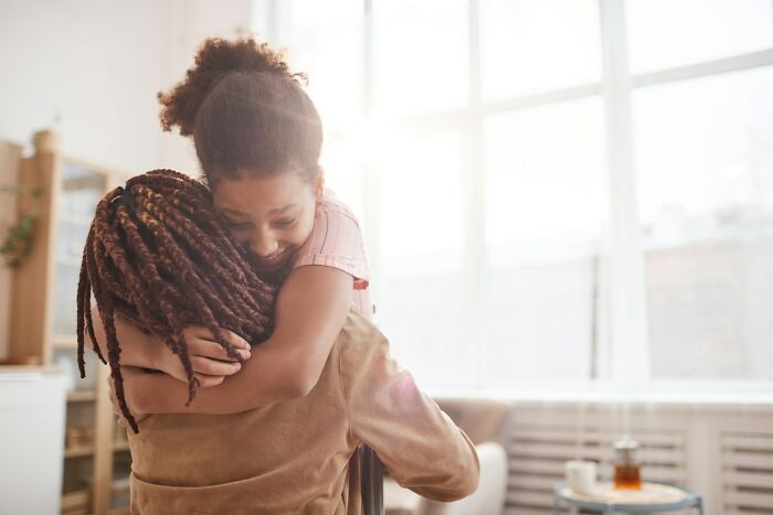 Parent and child sharing a warm embrace in a bright living room, illustrating parenting tips and tricks.