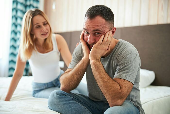 Couple in tense conversation on bed, illustrating relationship struggles and signs of a future breakup witnessed by wedding guests.
