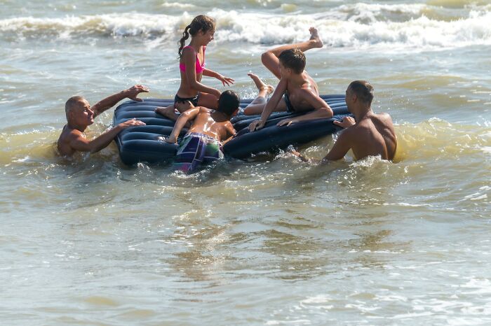 Children playing unsafely on an inflatable raft in the water, illustrating lack of survival instincts in kids.