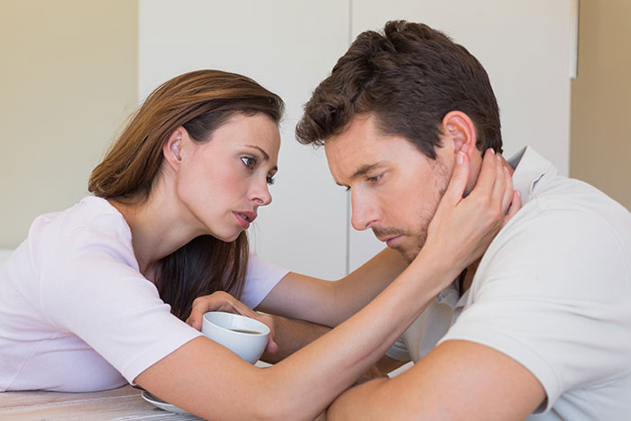 Couple in tense discussion at home, man feeling like a science experiment due to girlfriend keeping a log of his words.