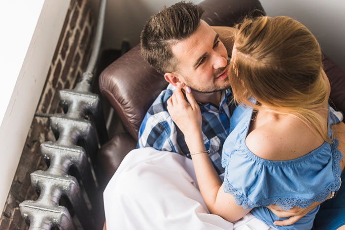 A couple sitting intimately, the woman gently touching the man's face. This image evokes feelings around affair and shocking details.