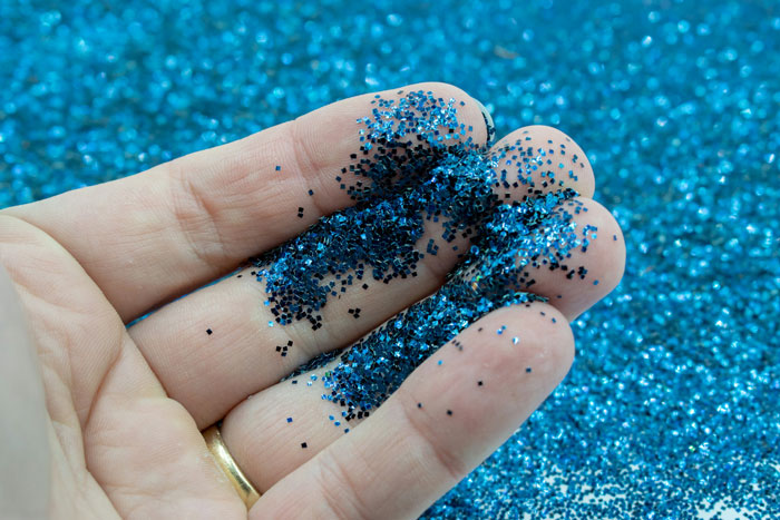 Close-up of hand holding blue glitter for revenge