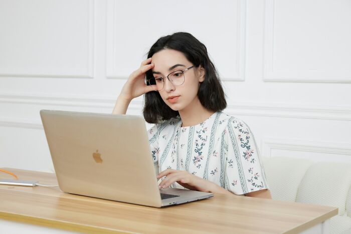 Young woman looking mortified while checking messages on a laptop, reacting to an accidental message sent out online.