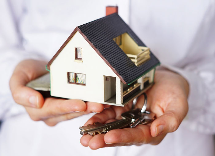 Person holding a small house model and keys symbolizing bankruptcy and penalties in a financial dispute case.
