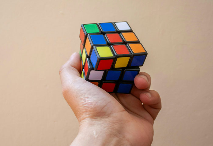 Hand holding a partially solved Rubik's Cube representing harmless but effective revenge on jerks concept.