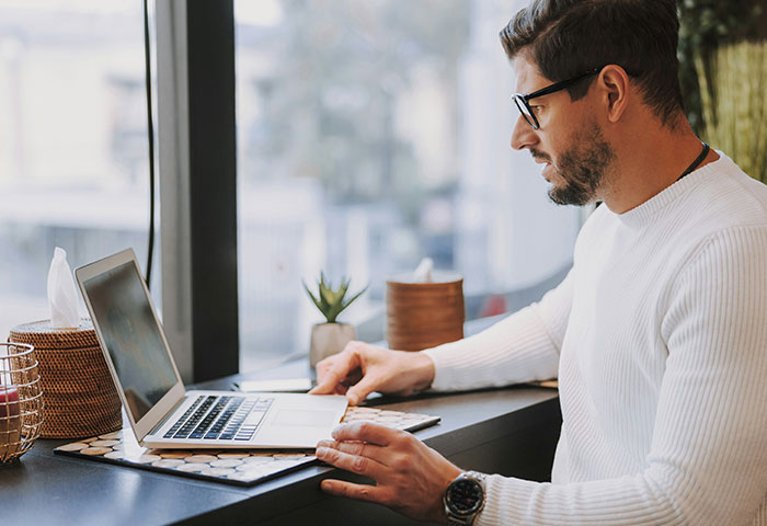 Man in glasses working on laptop at a desk, illustrating harmless but effective ways people got revenge on jerks.