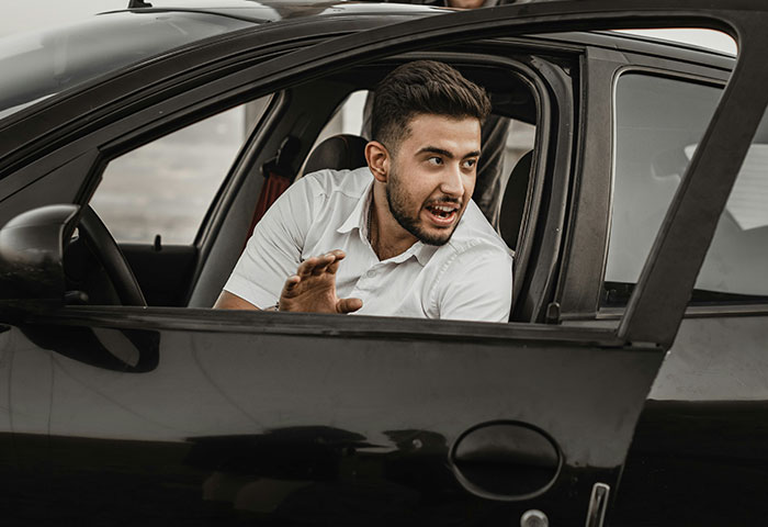Man in a car looking outside with an angry expression, depicting harmless but effective revenge on jerks.