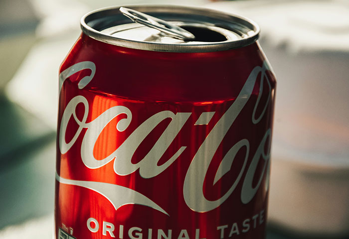 Red Coca-Cola can with original taste label on a blurred background, illustrating harmless but effective revenge on jerks.