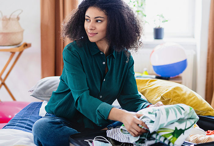 Woman folding clothes on a bed in a bright room, illustrating harmless but effective ways people got revenge on jerks.