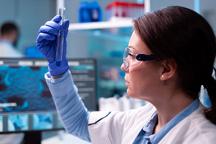 Scientist in a lab coat and gloves examining a test tube, highlighting DNA tests in a complex family dynamic scenario.