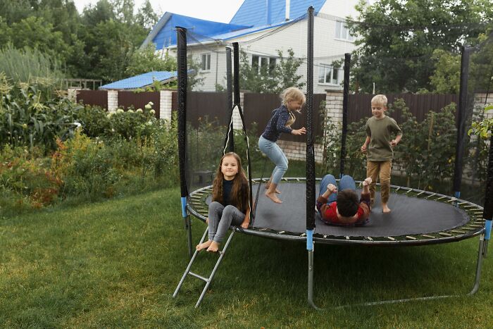 Children playing on a trampoline in a backyard, illustrating healthcare workers’ safety concerns for loved ones.