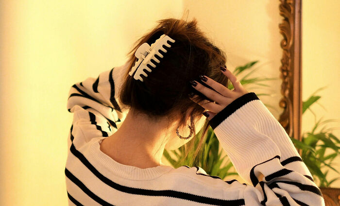 Woman with hair clip adjusting hair near a mirror, illustrating healthcare workers' advice on things loved ones should avoid.