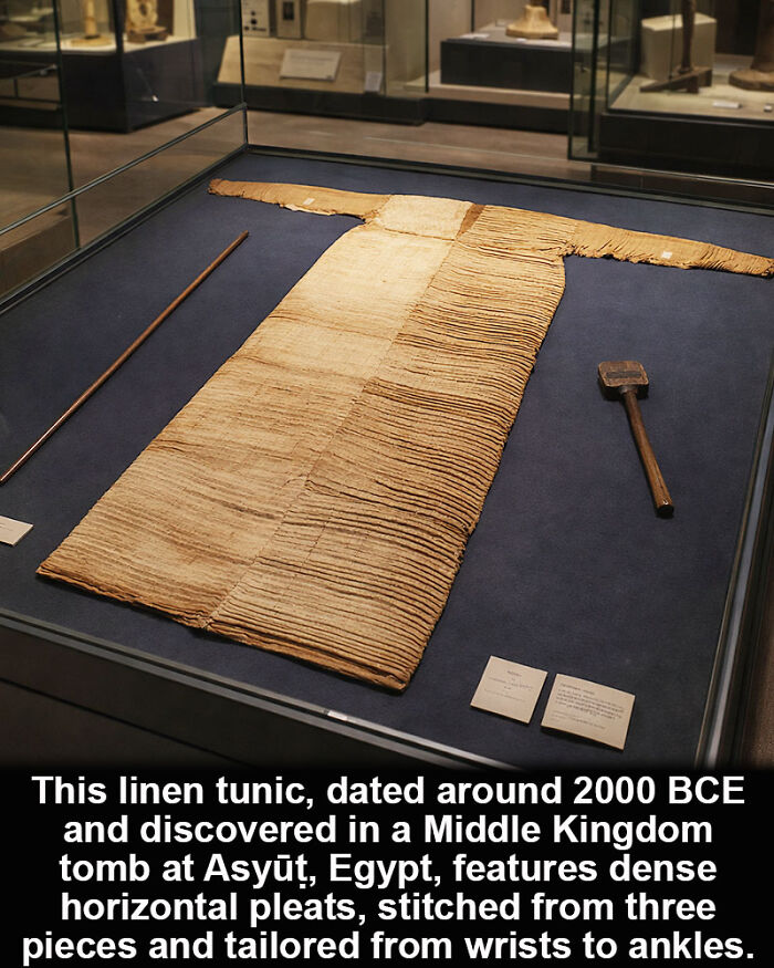 Ancient Egyptian linen tunic with dense pleats, a historical marvel preserved from around 2000 BCE in a museum display case.