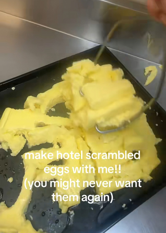 Um cozinheiro usando uma pinça para quebrar grandes pedaços de ovos pré-cozidos na cozinha de um hotel, com um texto revelando o processo.