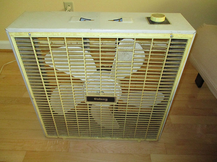 Vintage box fan on wooden floor, illustrating tips for an elevated and stress-free stay at a hotel environment.