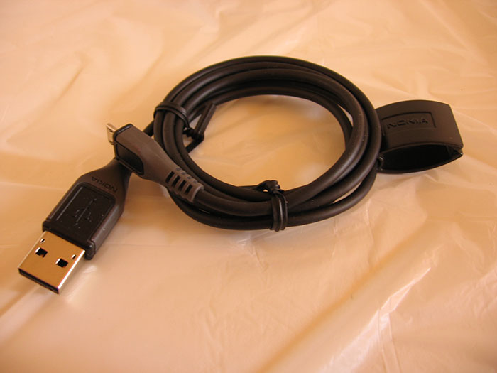 Black USB charging cable neatly coiled on a bed, illustrating tips for an elevated and stress-free hotel stay.