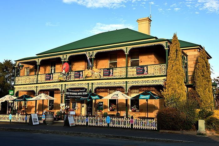 Historic hotel building with outdoor seating, umbrellas, and decorative railings offering an elevated and stress-free stay experience.
