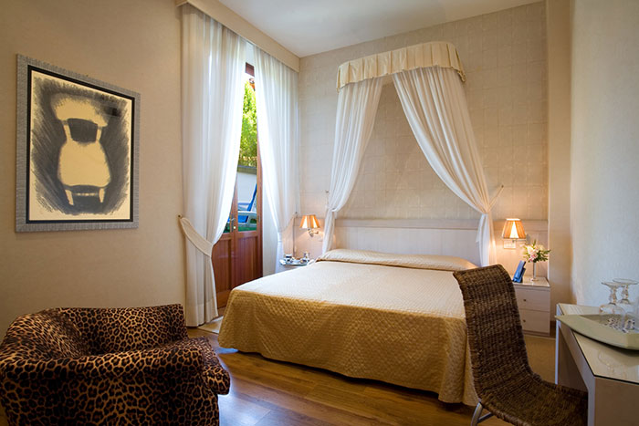Hotel room with canopy bed, leopard print chair, soft lighting, and open curtains showcasing tips for elevated hotel stays.