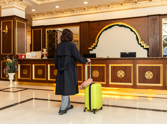 Guest with bright suitcase at hotel reception desk, illustrating tips for an elevated and stress-free hotel stay.