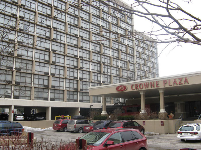 Exterior view of Crowne Plaza hotel with parked cars, illustrating tips for an elevated and stress-free hotel stay.