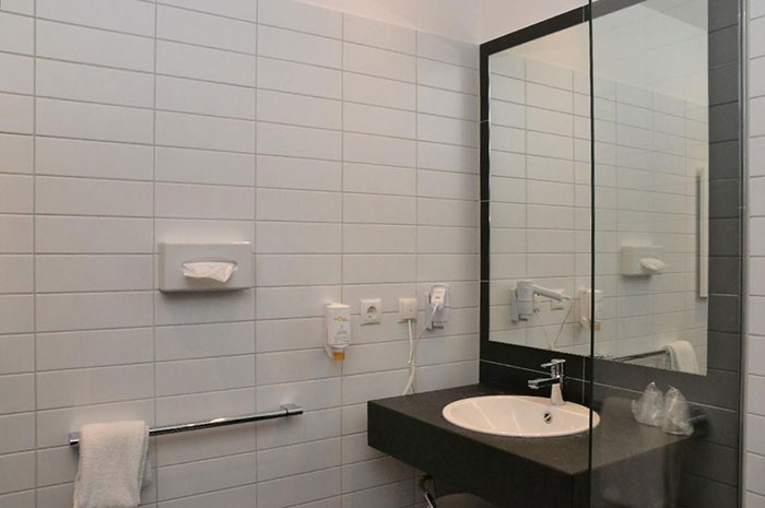 Modern hotel bathroom with sink, mirror, clean towels, and toiletries for an elevated and stress-free stay