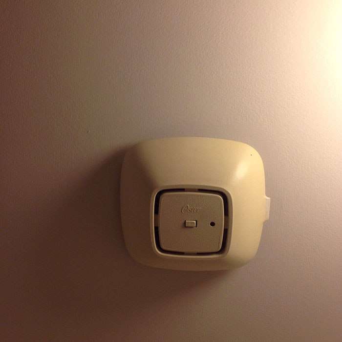 Wall-mounted hotel thermostat control in a neutral room setting for an elevated and stress-free stay at a hotel.