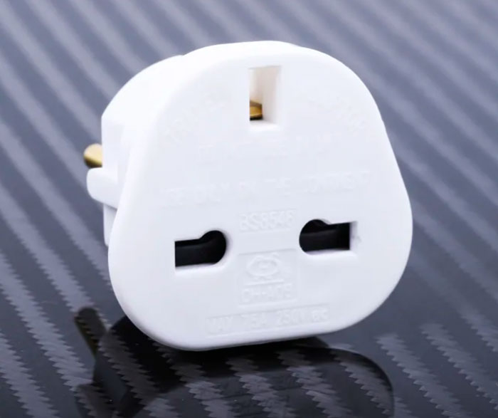 White universal travel adapter on a dark textured surface, helpful for an elevated and stress-free hotel stay tips.