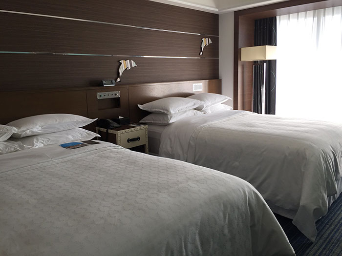 Two neatly made hotel beds in a modern room with soft lighting, illustrating tips for an elevated and stress-free stay.