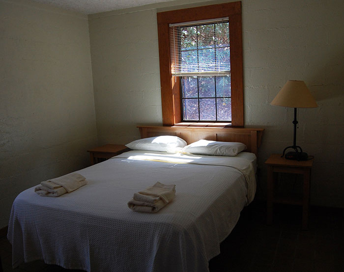 Cozy hotel room with neatly made bed, fresh towels, wooden furniture, and natural light for an elevated stay experience.