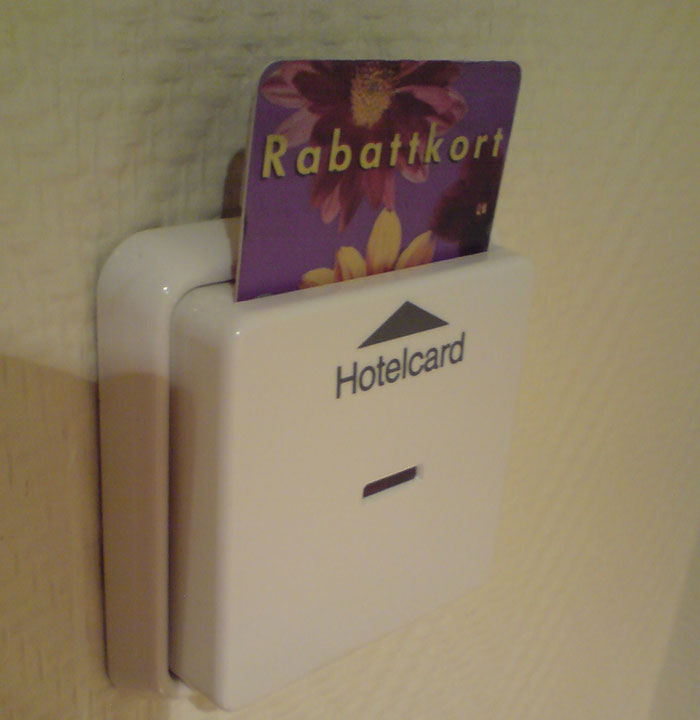 Hotel key card inserted in a wall-mounted white card holder, illustrating tips for an elevated and stress-free hotel stay.
