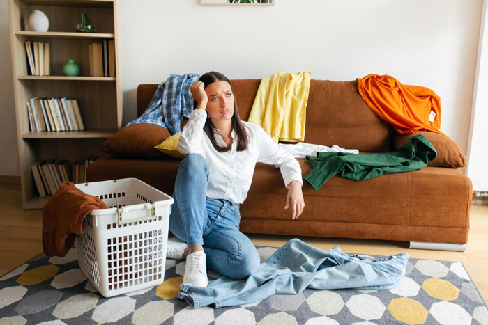 A frustrated woman surrounded by messy laundry, symbolizing the struggles of a wife after a cervical cancer diagnosis.