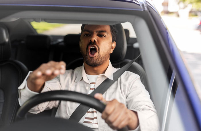 Man having outburst inside car, expressing frustration, conveying anger unrelated to mustard or condiment.