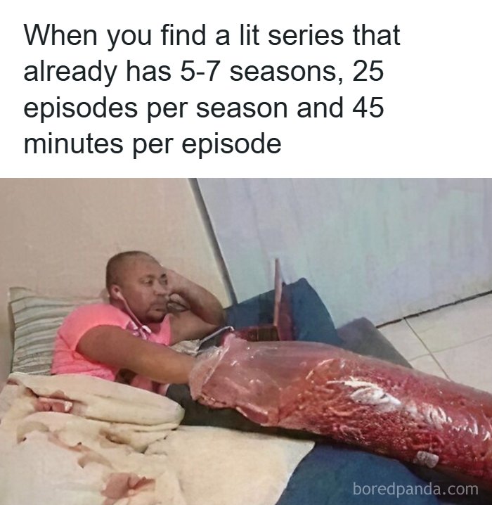 Man lying on bed watching laptop with a large bag of snacks, illustrating memes as a reason people pay for the internet.