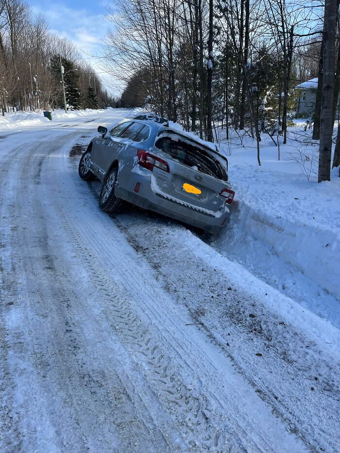 Silver car stuck in a snowy ditch on a rural icy road, showcasing unexpected intelligence in a winter landscape.