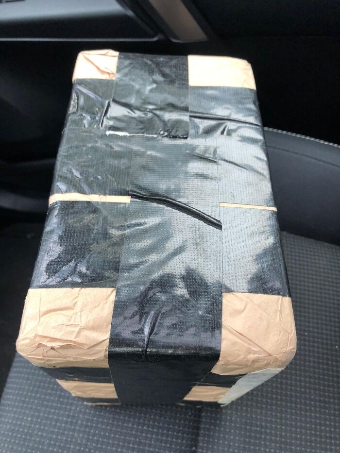 Box wrapped in brown paper and black tape, resembling a strange and disturbing object found in elevator pits.