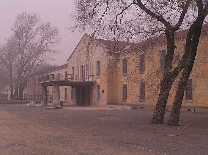 Old abandoned building surrounded by bare trees in foggy weather illustrating horrifying historical facts.