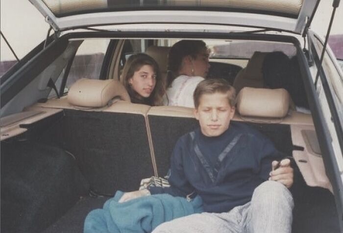 Group of friends sitting in car trunk reminisce