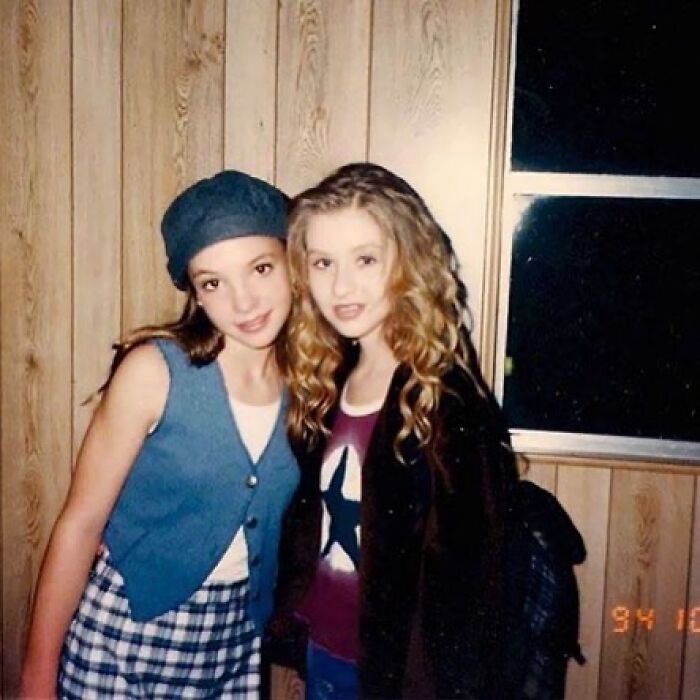 Two young female friends posing in wood-paneled room before fame