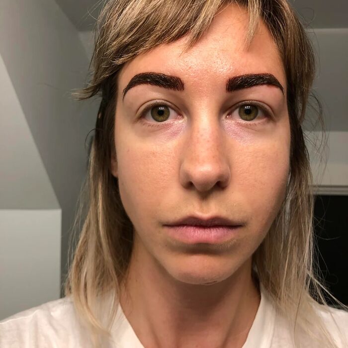 A woman with overly dark, thick eyebrows from a beauty disaster, looking at the camera with a neutral expression.
