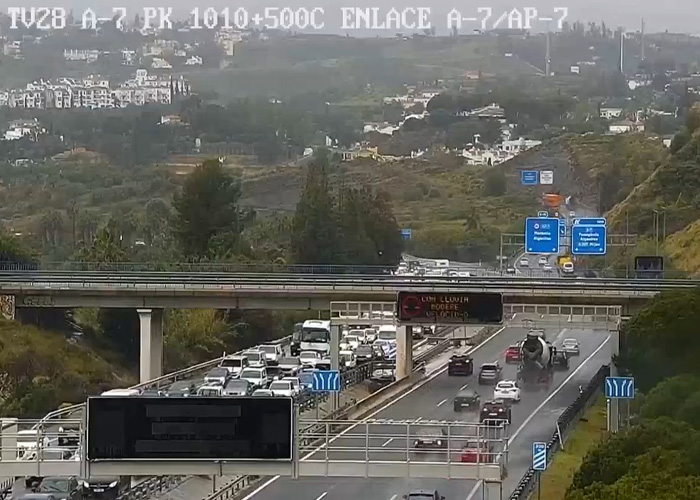 Tráfego rodoviário com casas nas encostas ao fundo durante um dia claro, relacionado aos avistamentos de gostosas na procissão da Páscoa espanhola.