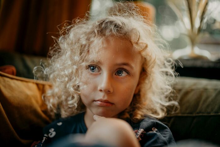 Young child with curly hair and a thoughtful expression, illustrating the impact of weaponized incompetence in relationships.
