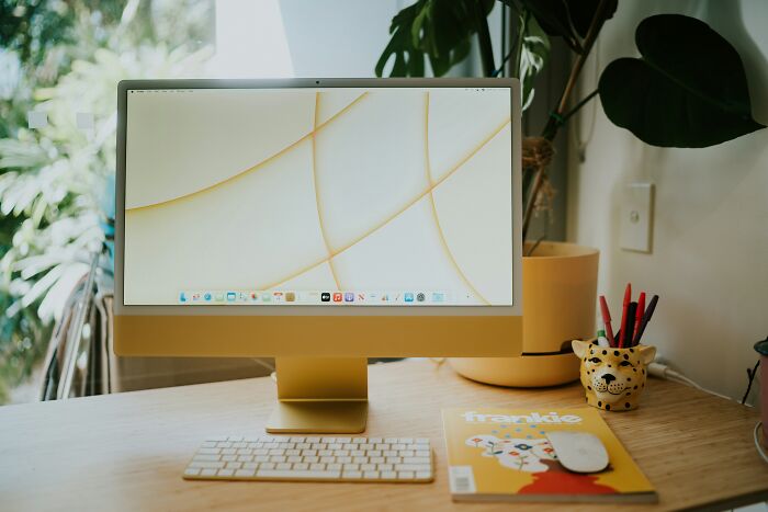 Modern yellow iMac desktop setup with magazine and pens. A calm space to reflect on friendship betrayals.