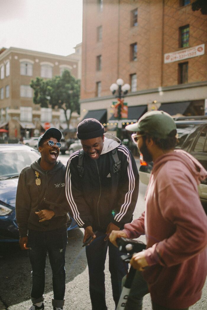 Three young men laughing together on a city street, capturing moments of former bullies reconnecting and reflecting.