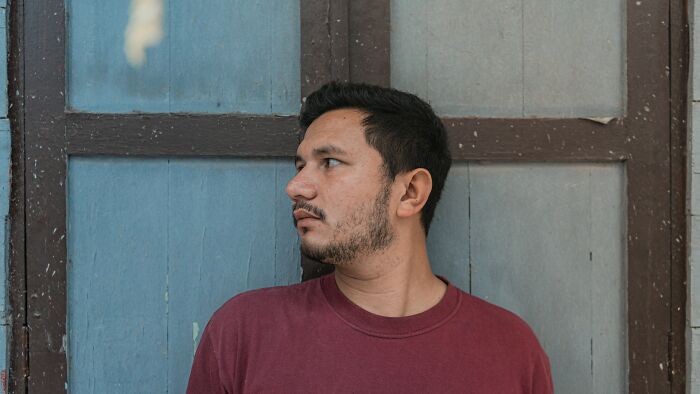 Man in a red shirt looking to the side, representing people who met former bullies and childhood challenges.